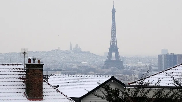 На дахах будинків у Парижі видніється сніг.