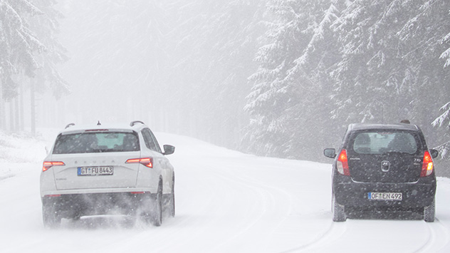 Autos sind auf den Feldberg im Taunus bei Schneefall auf der Straße unterwegs.