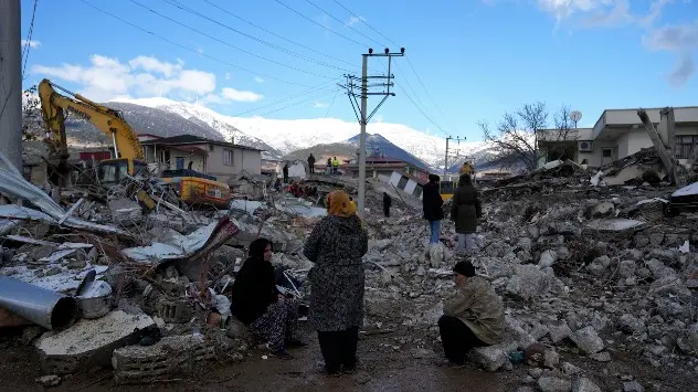 People sit on the rubble as emergency rescue teams search beneath destroyed buildings in Nurdagi on February 7th.