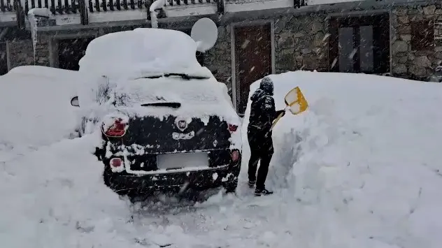 Man shovels snow off of vehicle and driveway