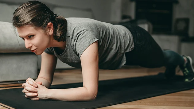 "Plank": Auf dem Bauch liegend sind die Ellenbogen auf Schulterhöhe und die Beine hüftbreit aufgestellt.