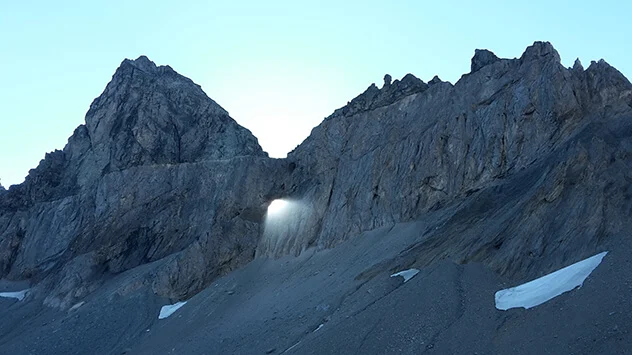Sonnenstrahlen fallen durch ein Felsenauge in der Sardona Tektonikarena