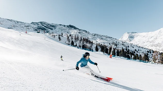 Eine Frau fährt eine Skipiste hinab. 