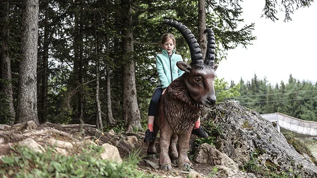 Mädchen sitzt auf Holzfigur