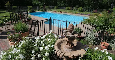 gated pool with landscaping and fountain