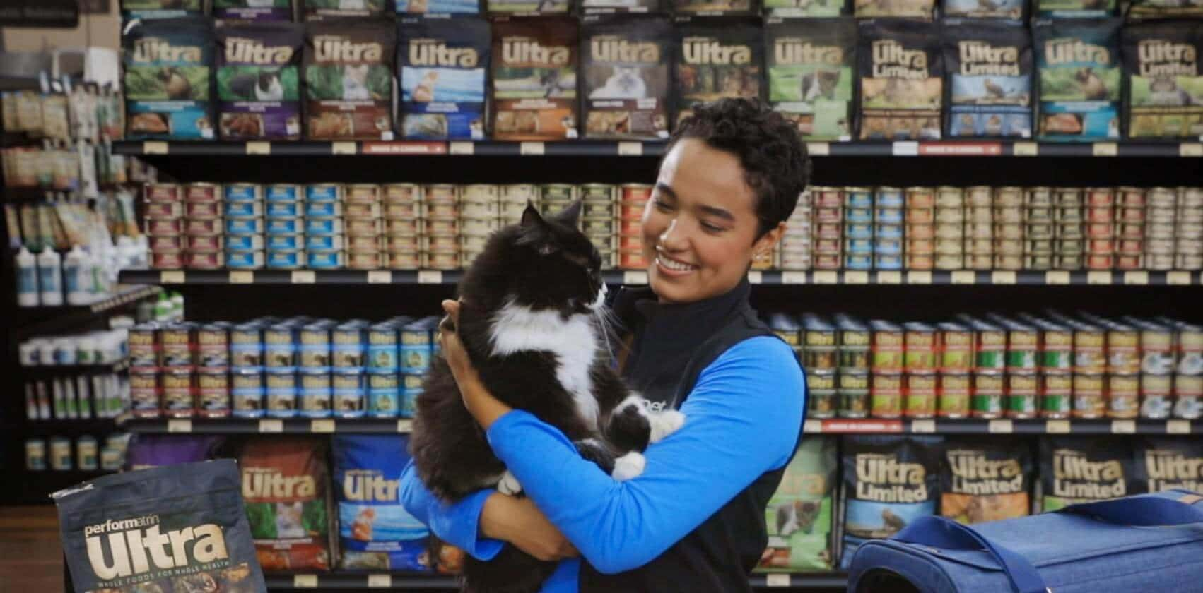 A cute tuxedo cat gets some cuddles from a Pet Valu Animal Care expert in a Pet Valu store.