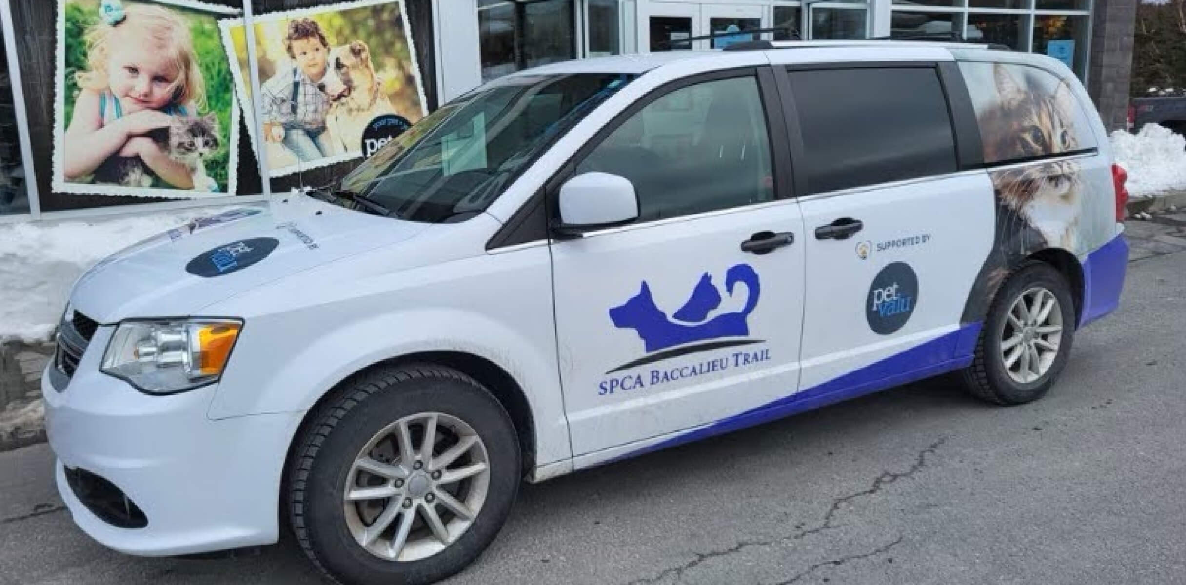 A white van with SPCA and Pet Valu logos on it is parked outside a Pet Valu store