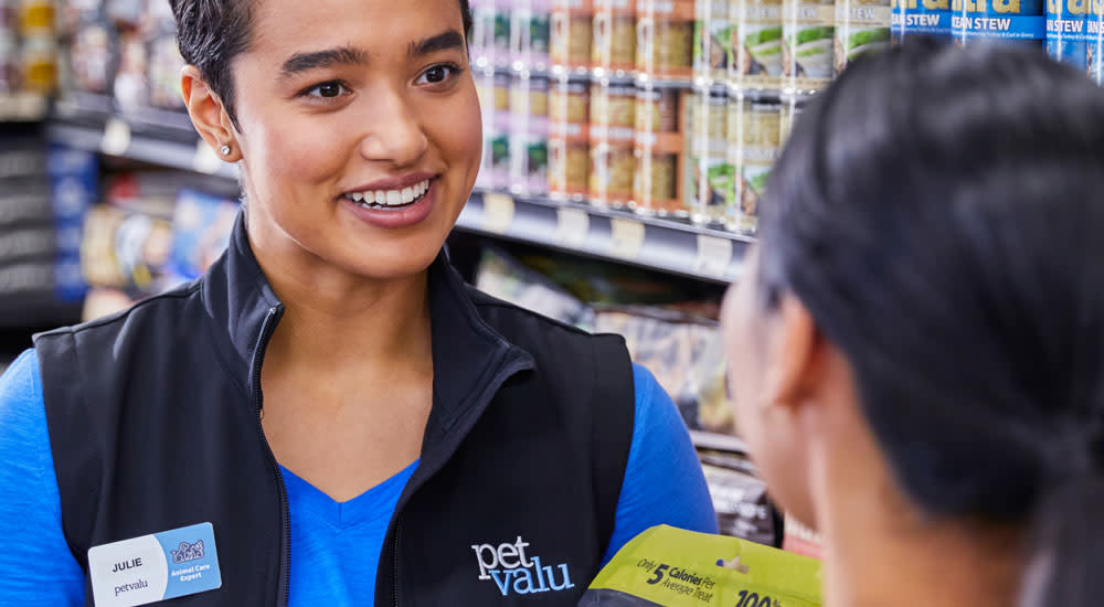 A Pet Valu employee offering advise about pet food to a customer