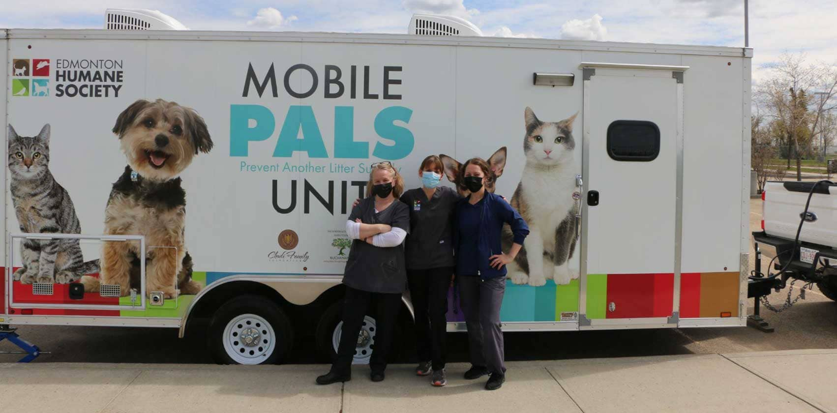 Three shelter works pose in front of a trailer decorated with images of cats and dogs