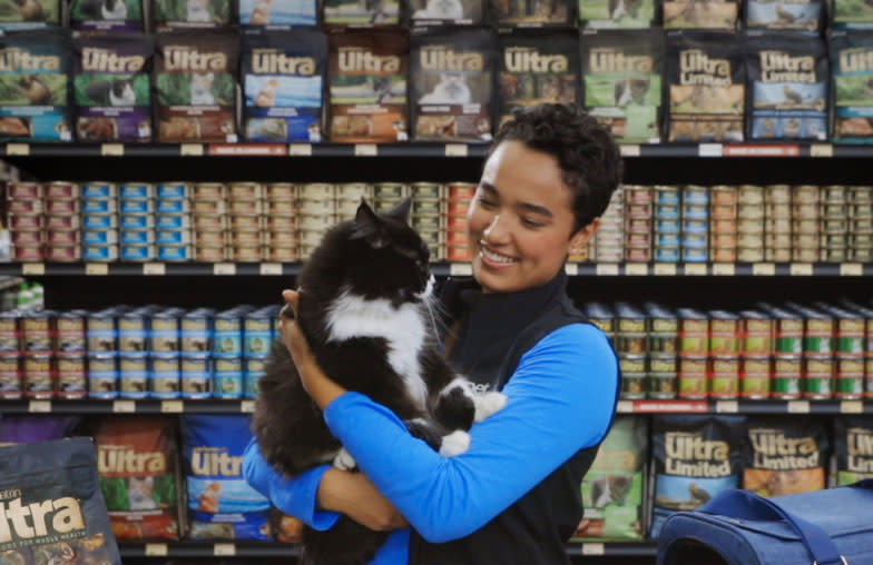 A cute tuxedo cat gets some cuddles from a Pet Valu Animal Care expert in a Pet Valu store.