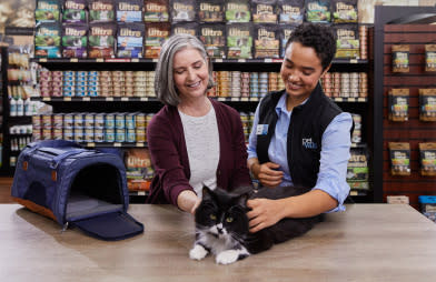 Pet Valu Animal Care expert with a Devoted pet lover and a pet cat and cat carrier in a Pet Valu store