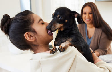 Animal care that can reduce pet costs over time - A mother watching her daughter play with a dog