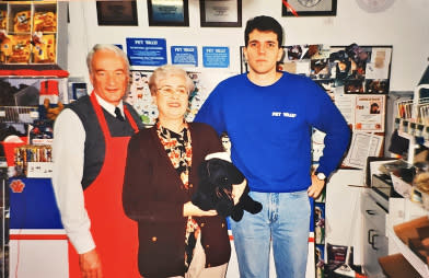 A son and his father, as well as his mother holding a dog, stand in a Pet Valu store backroom