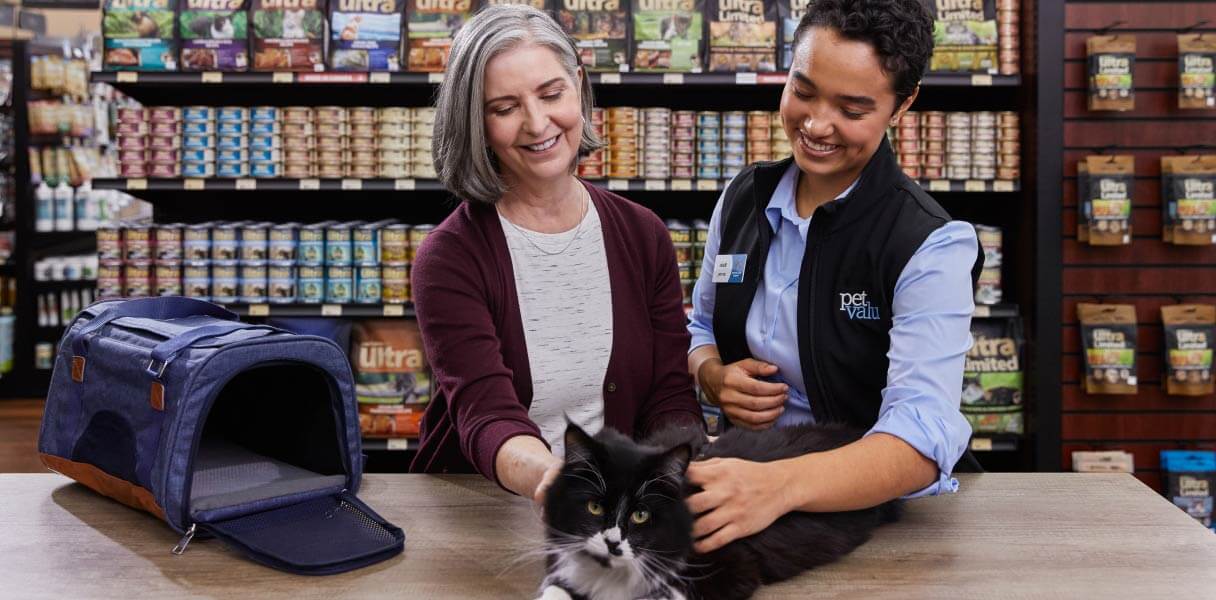 Pet Valu Animal Care expert with a Devoted pet lover and a pet cat and cat carrier in a Pet Valu store