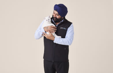 A pet staff member smiles while holding a white pet cat