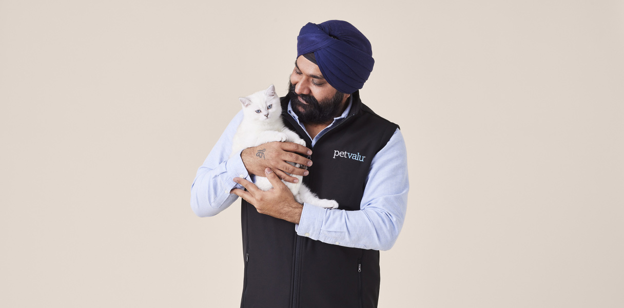 A pet staff member smiles while holding a white pet cat