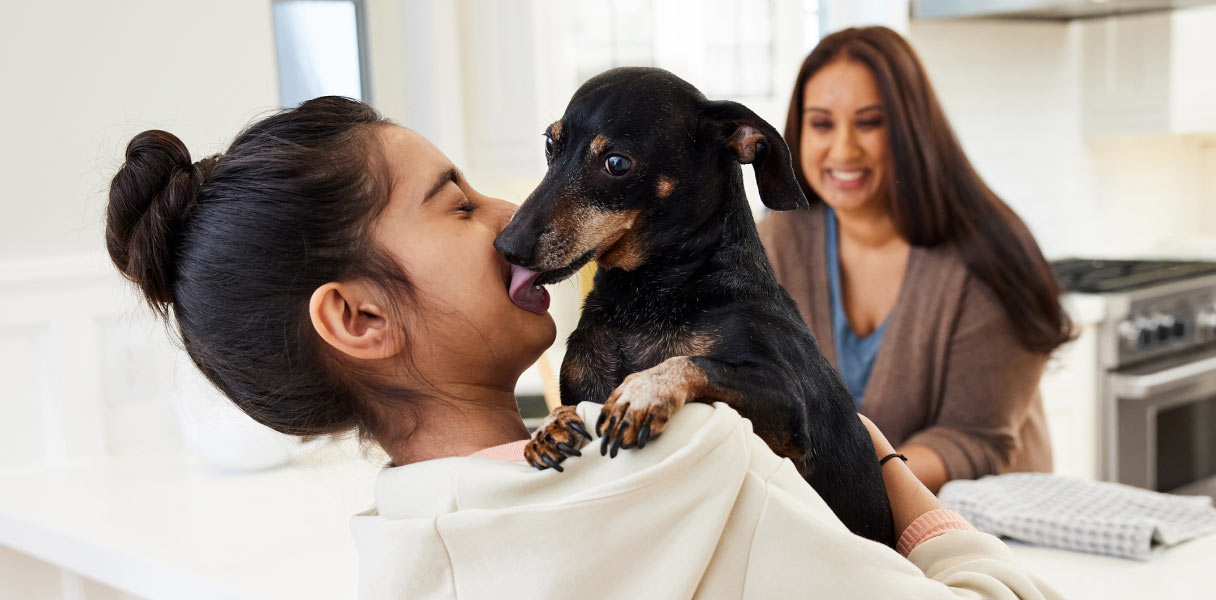 Animal care that can reduce pet costs over time - A mother watching her daughter play with a dog