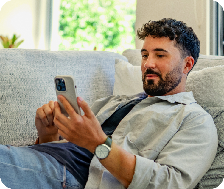 Mann liegt auf Sofa und schaut auf sein Handy