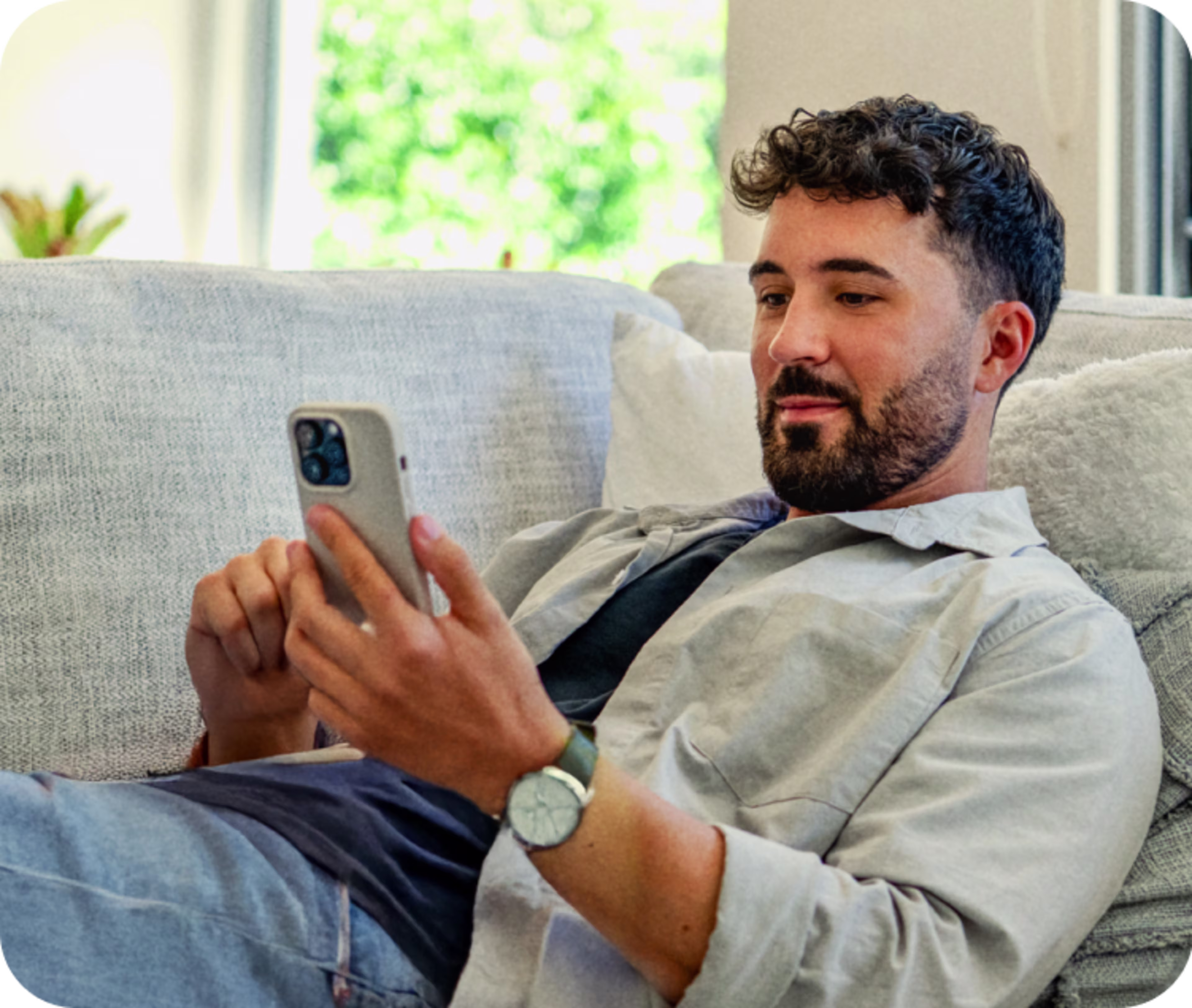 Mann liegt auf Sofa und schaut auf sein Handy