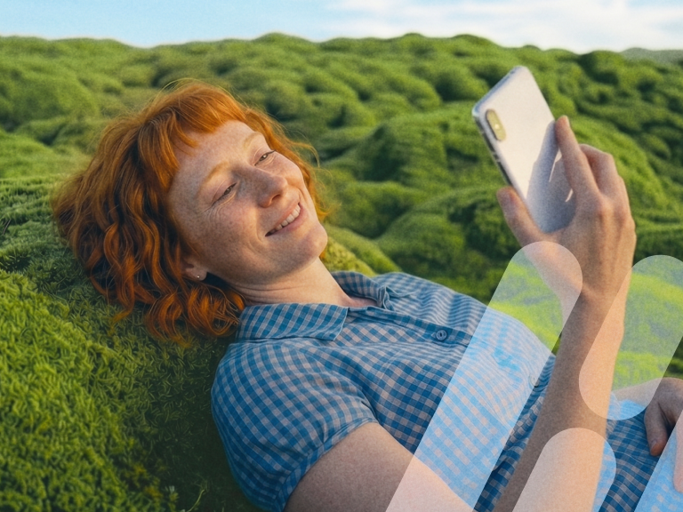 Frau liegt im Moos und schaut lächelnd auf ihr Smartphone.