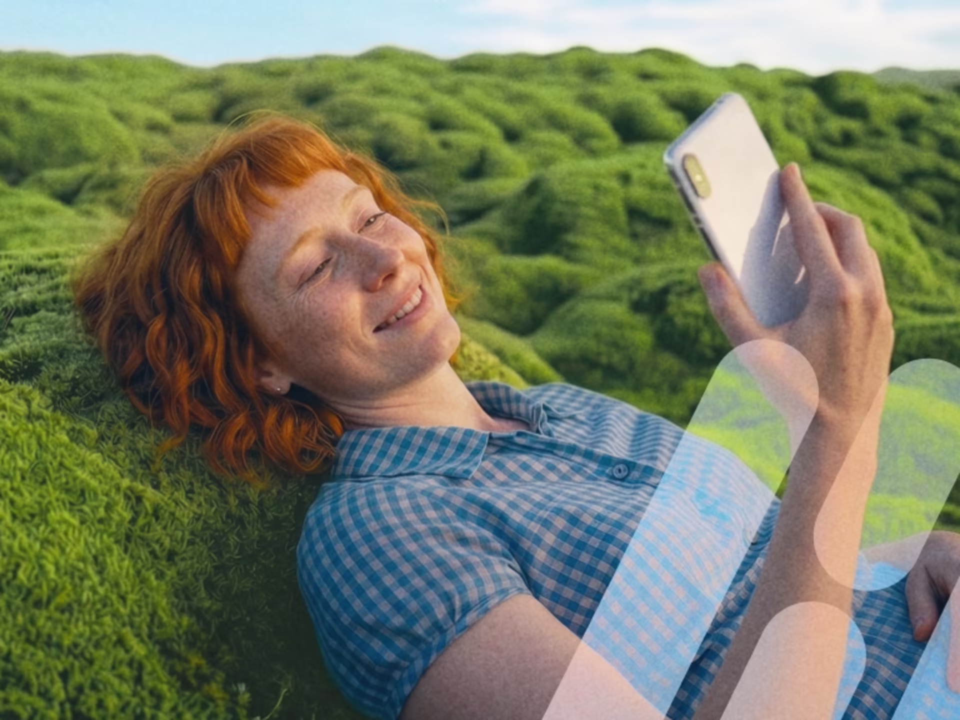 Frau liegt im Moos und schaut lächelnd auf ihr Smartphone.