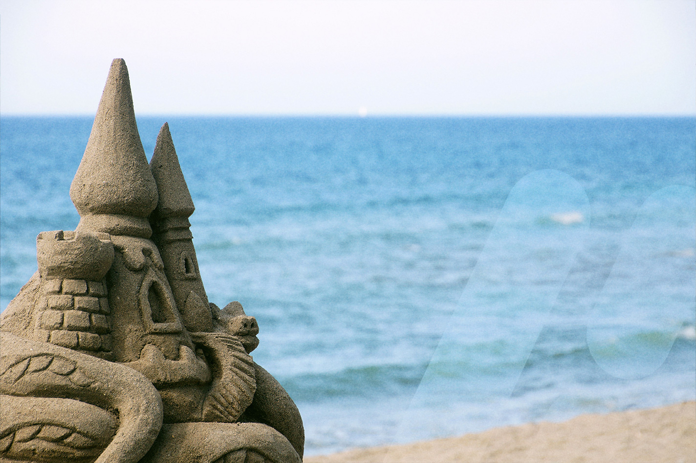 Sandburg am Strand mit dem Meer im Hintergrund.