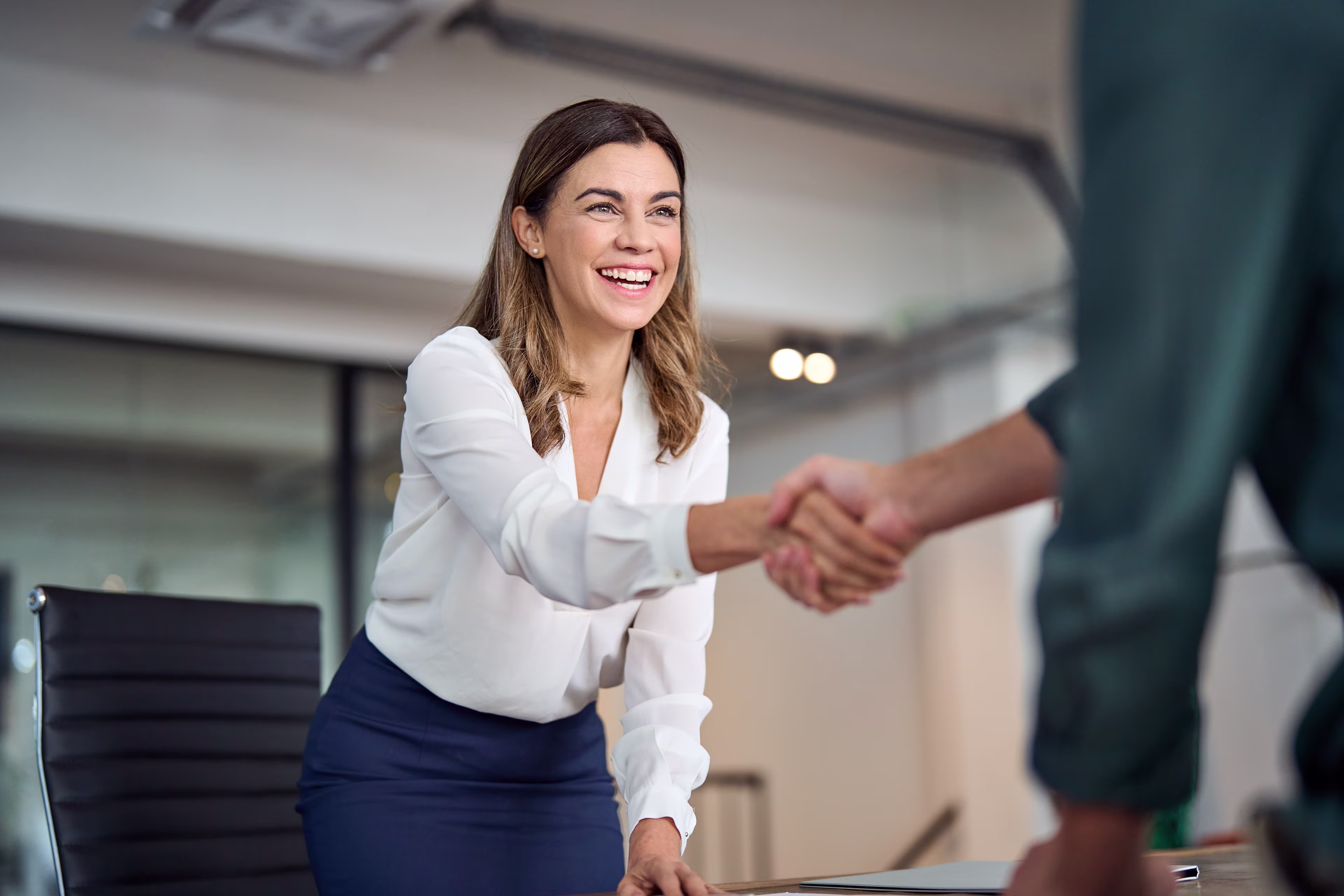 Eine lächelnde Frau schüttelt die Hand eines Geschäftspartners