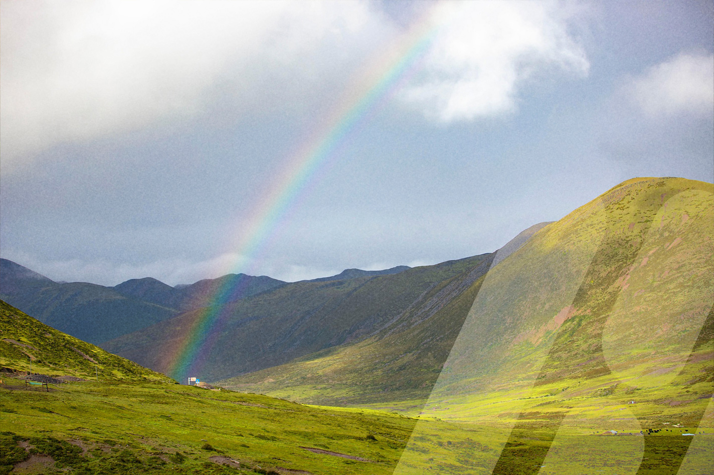 Regenbogen über einer grünen Berglandschaft.