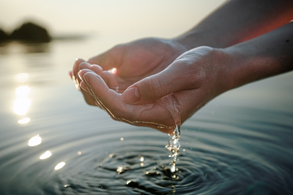 Hände schneiden sauberes Frischwasser aus einem See