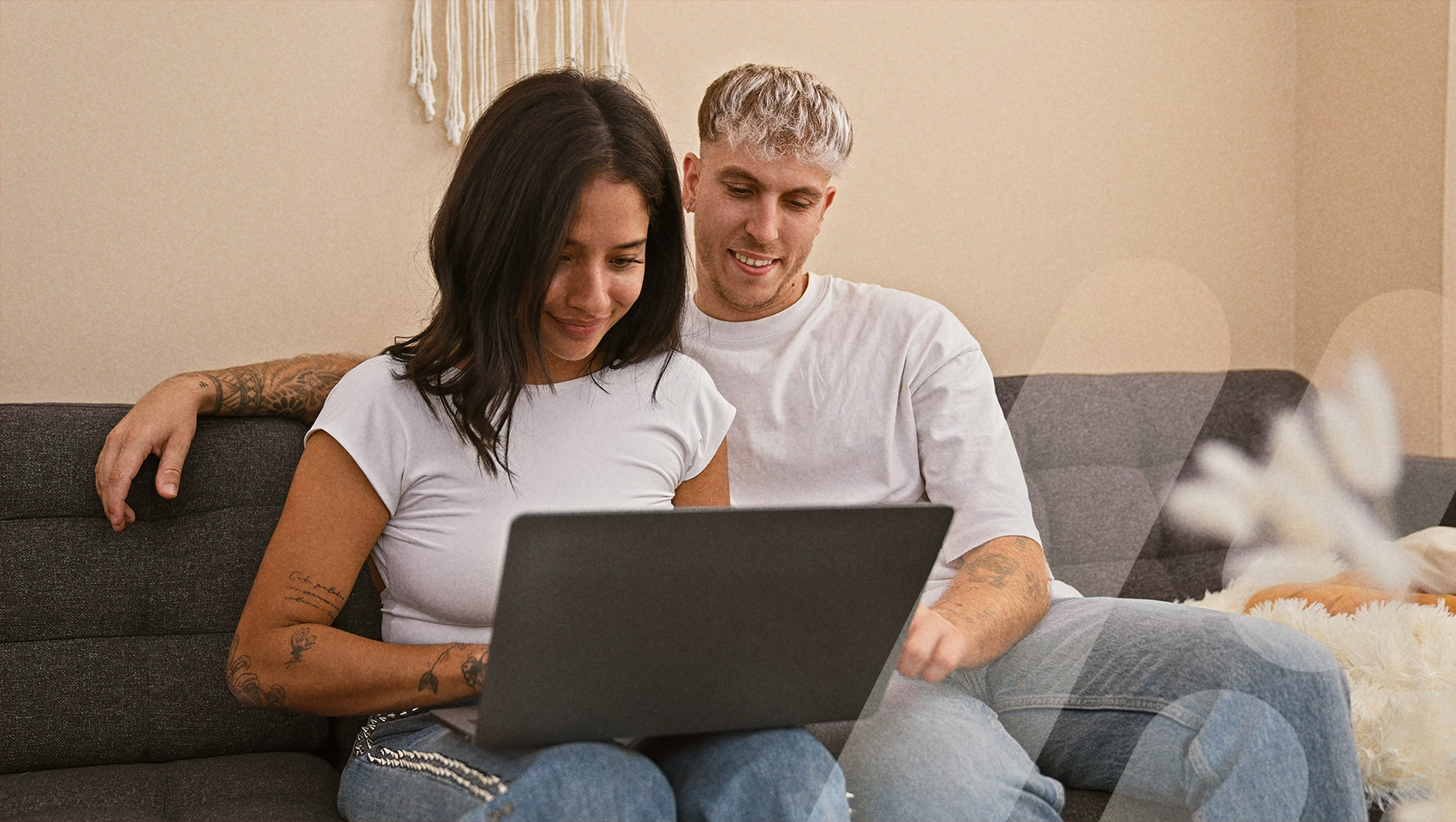 Paar sitzt auf der Couch vor Laptop
