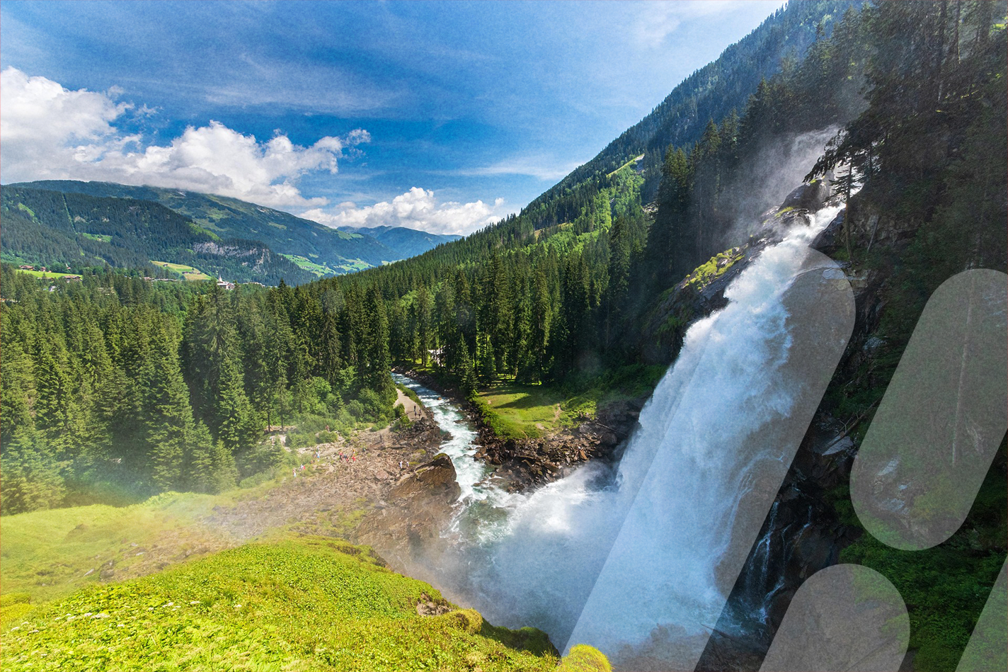 Großer Wasserfall stürzt einen bewaldeten Berghang hinab in einen Fluss. Umgeben von grünen Wiesen, dichten Nadelwäldern und Bergen unter blauem Himmel mit weißen Wolken.
