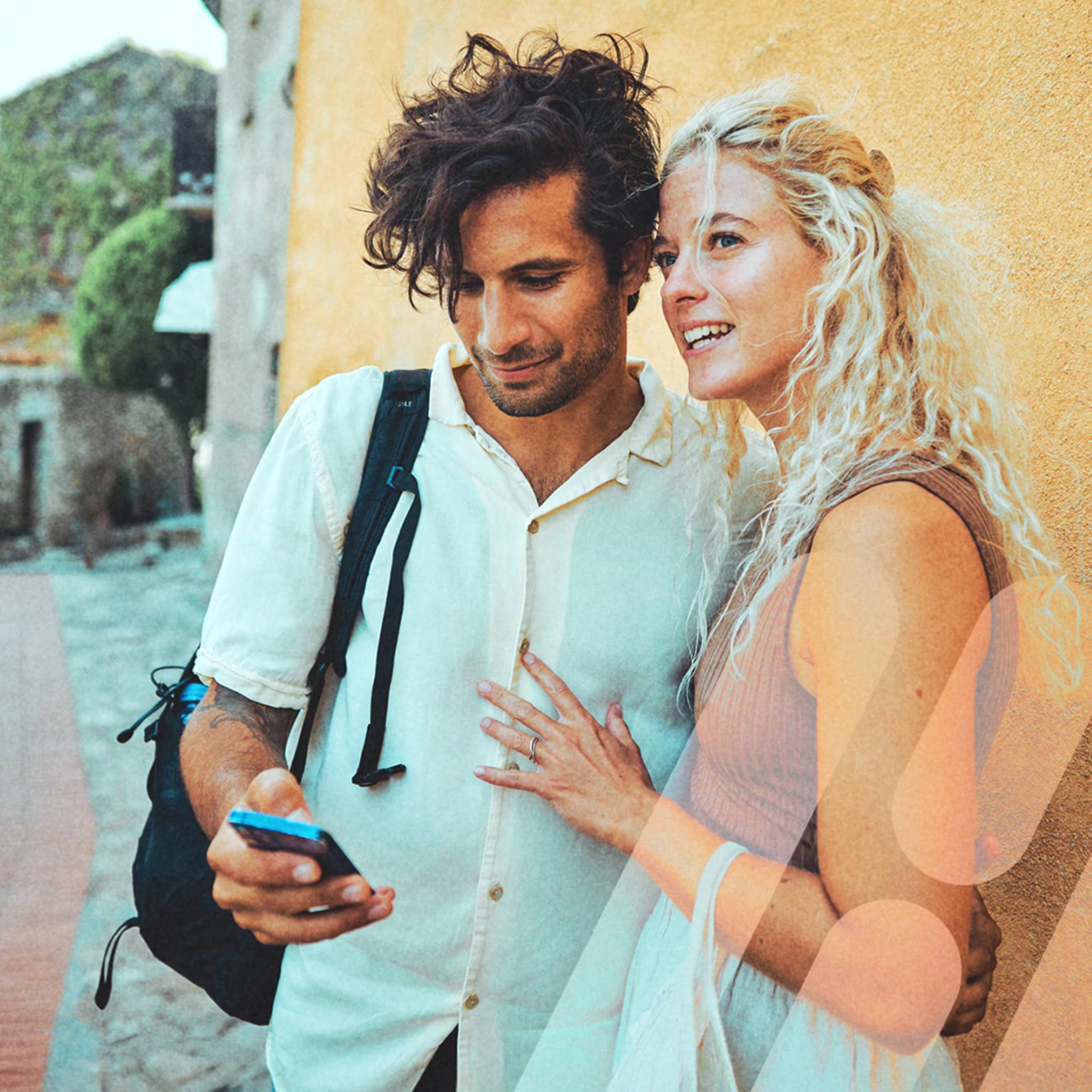 Ein Mann schaut auf sein Handy, während er eine Frau im Arm hält.