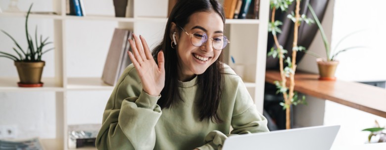 Woman waving at laptop screen