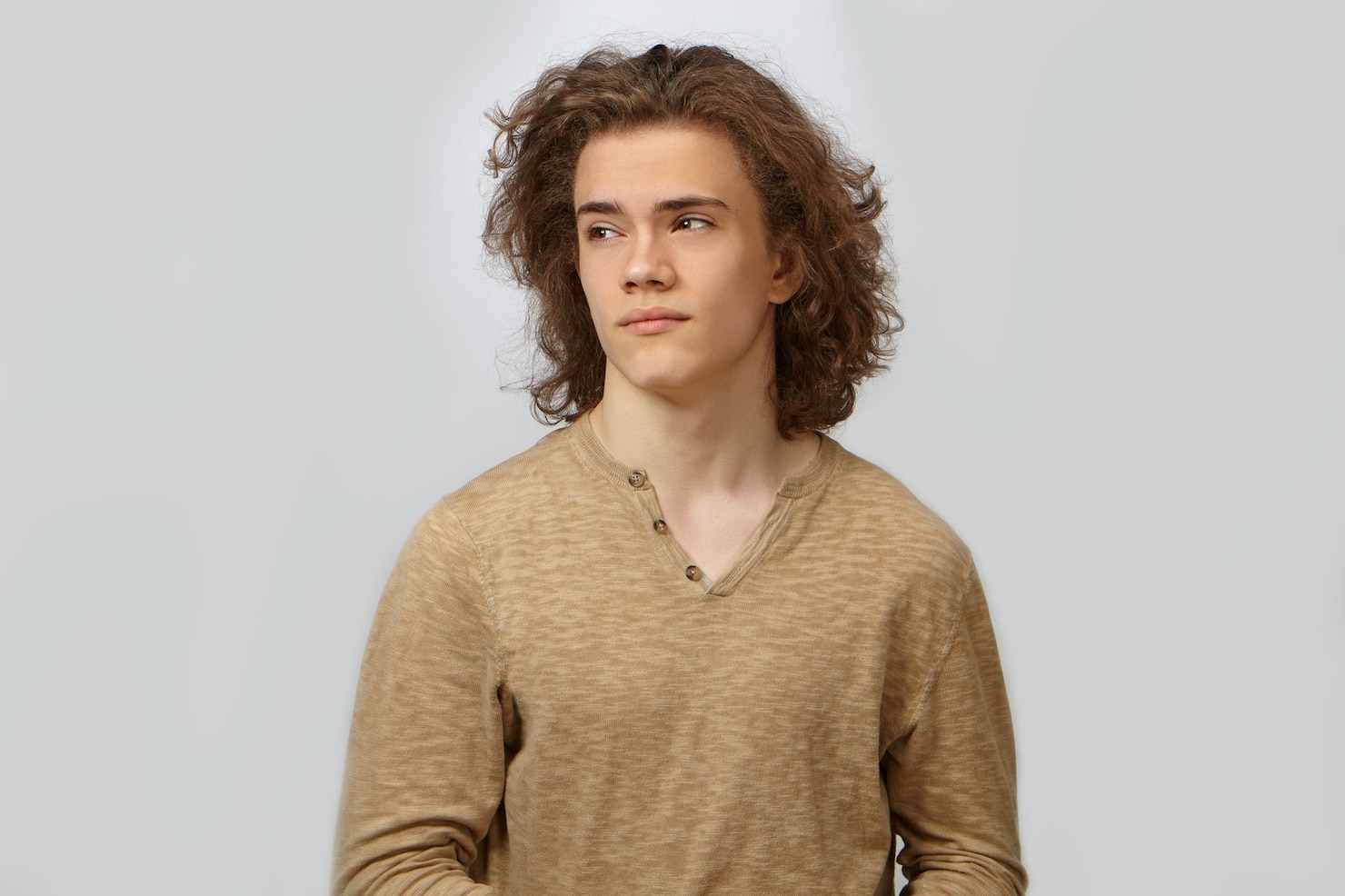 portrait-attractive-young-european-guy-with-smooth-face-brown-eyes-curly-hairdo-posing-blank-wall-looking-sideways-dressed-beige-shirt-people-style-fashion-concept 343059-1560