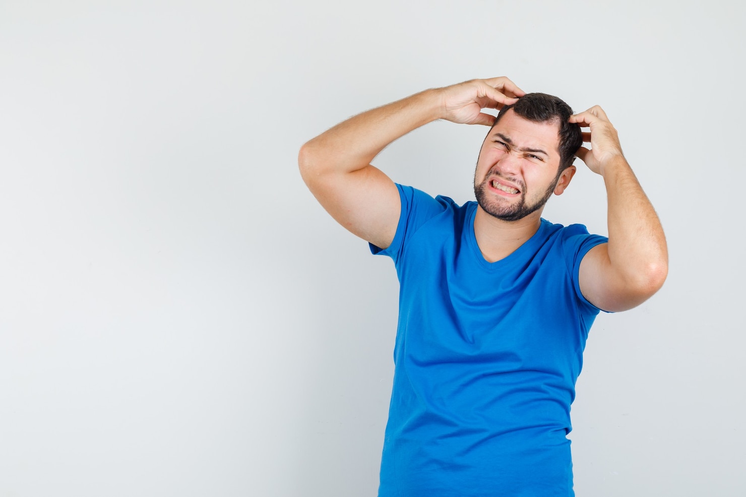 young-male-holding-fingers-head-blue-t-shirt-looking-irritated 176474-16229