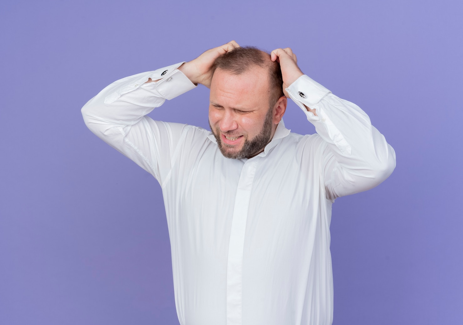 upset-bearded-man-wearing-white-shirt-touching-his-head-being-frustrated-standing-blue-wall 141793-56123