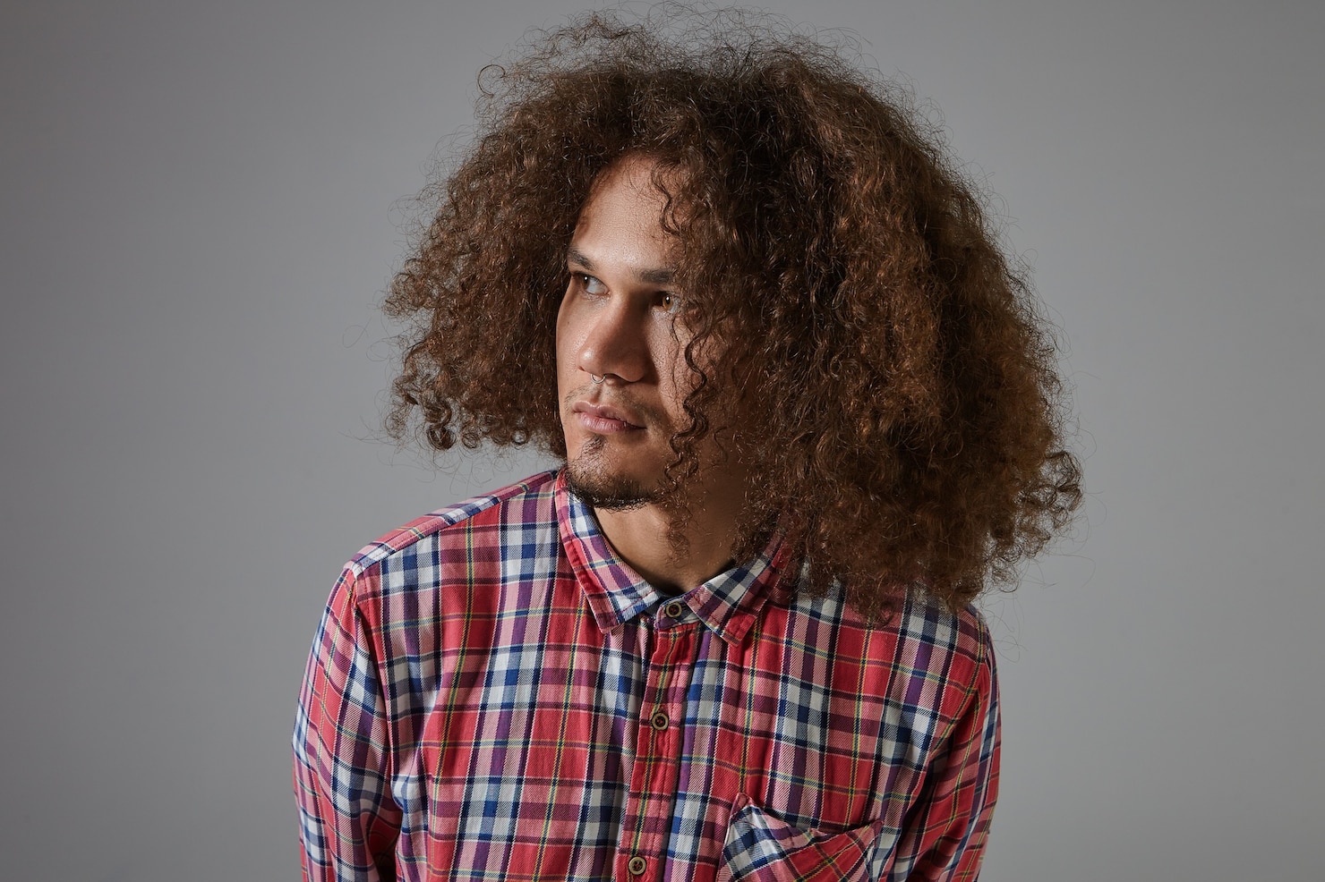 handsome-attractive-young-mixed-race-unshaven-male-with-tanned-skin-curly-loose-hair-pierced-nose-posing-looking-away-with-serious-facial-expression-dressed-plaid-shirt 343059-3161