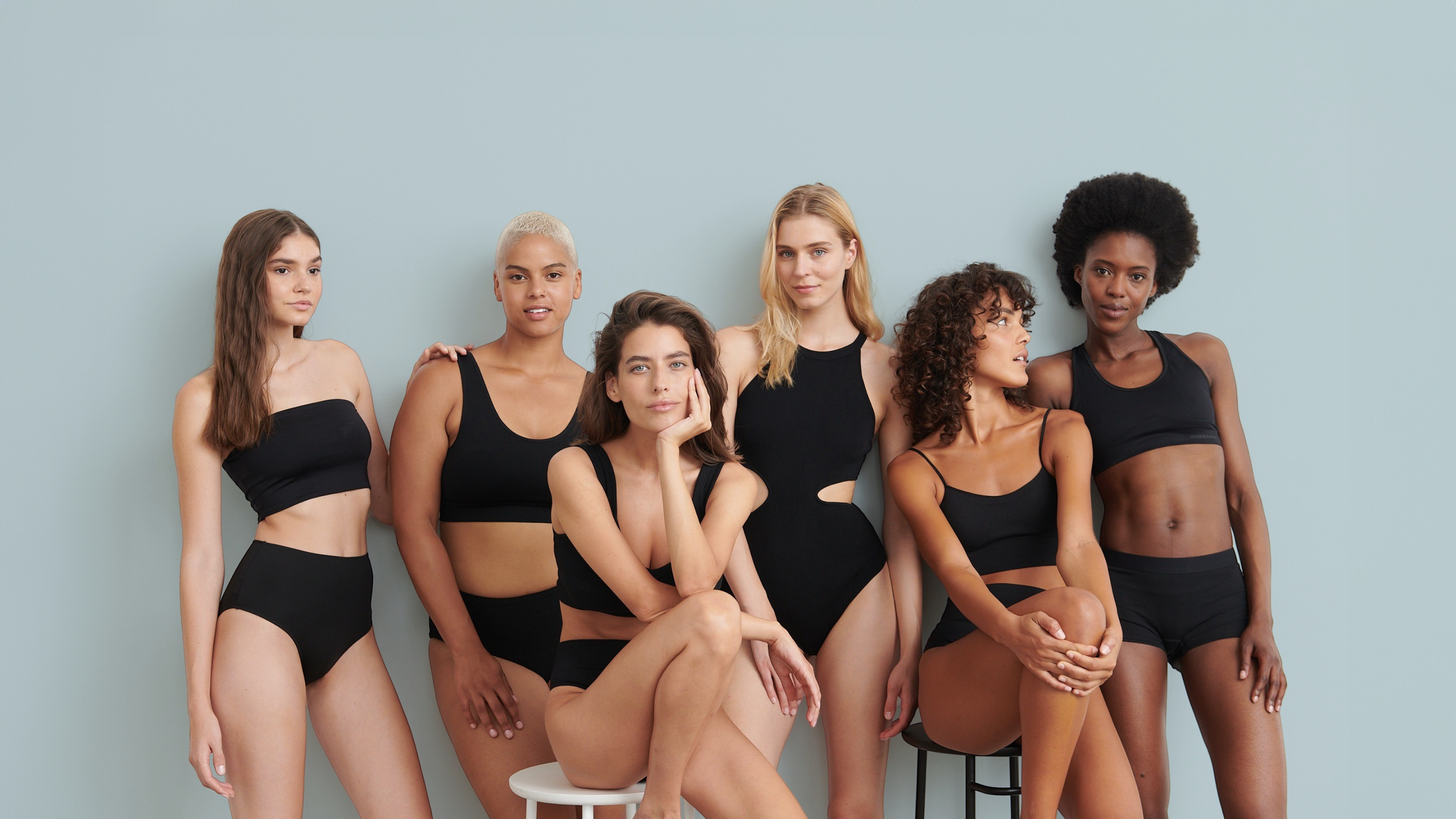 Eine Gruppe von sechs sitzenden und stehenden Frauen in schwarzen sportlichen Bikinis.