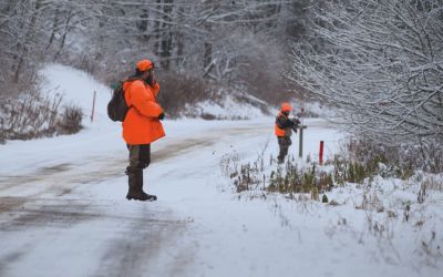 Hunters recreating at LEEK Hunting and Mountain Preserve follow a road while hiking in the winter.