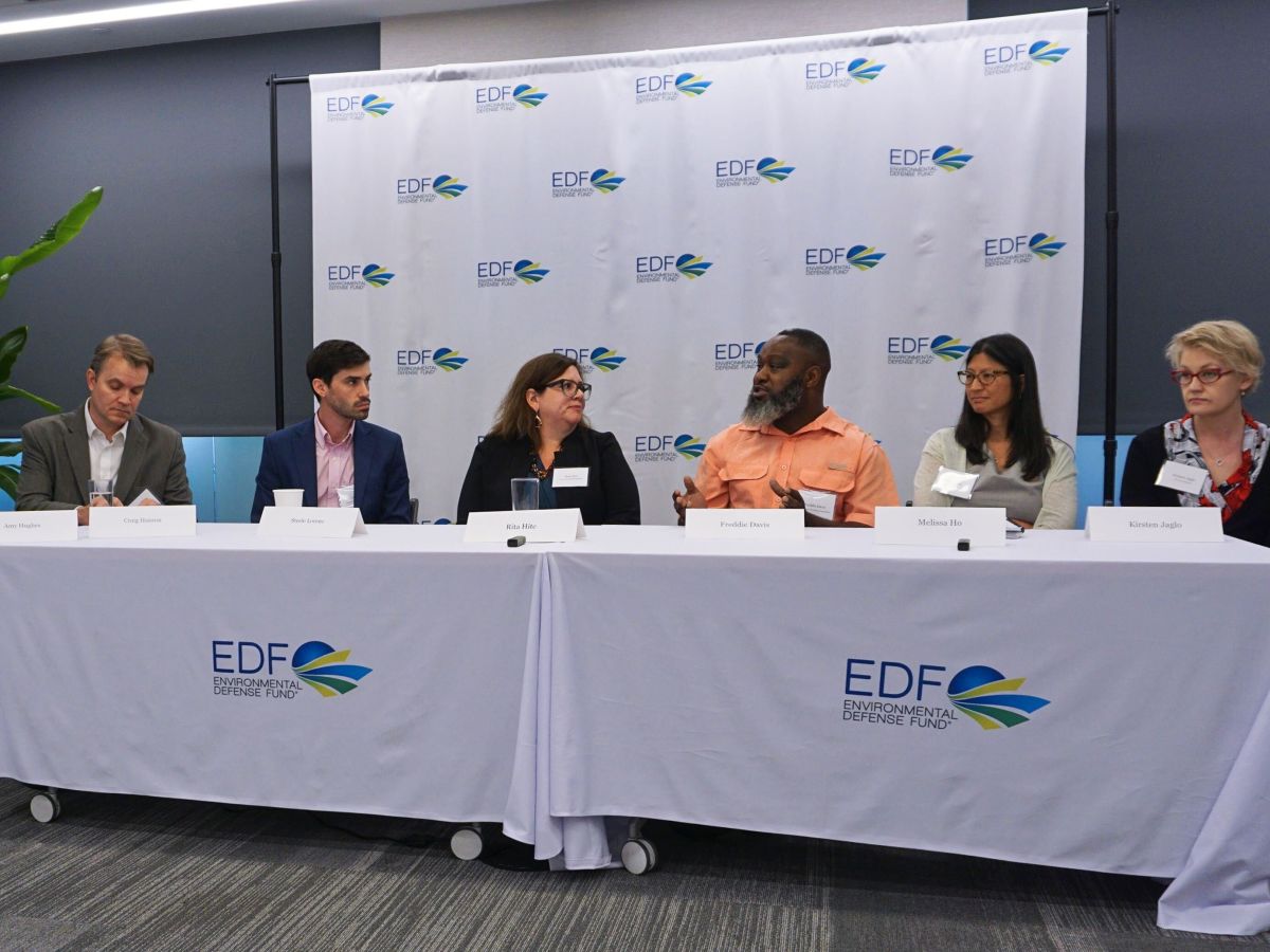 Six people sit facing out behind a long table that says EDF on it.