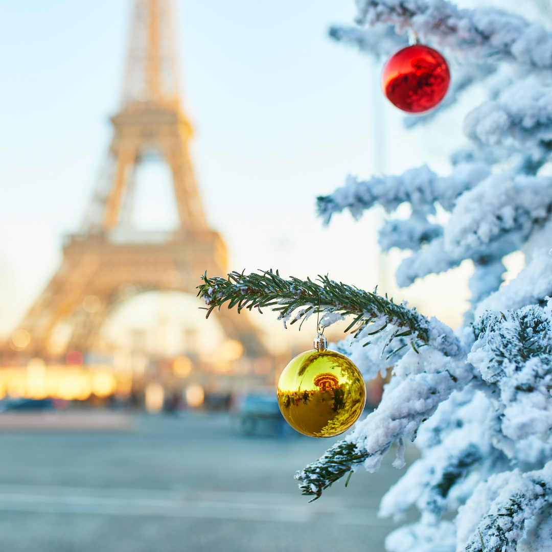 A snowy Eiffel Tower behind a Christmas tree covered in baubles.