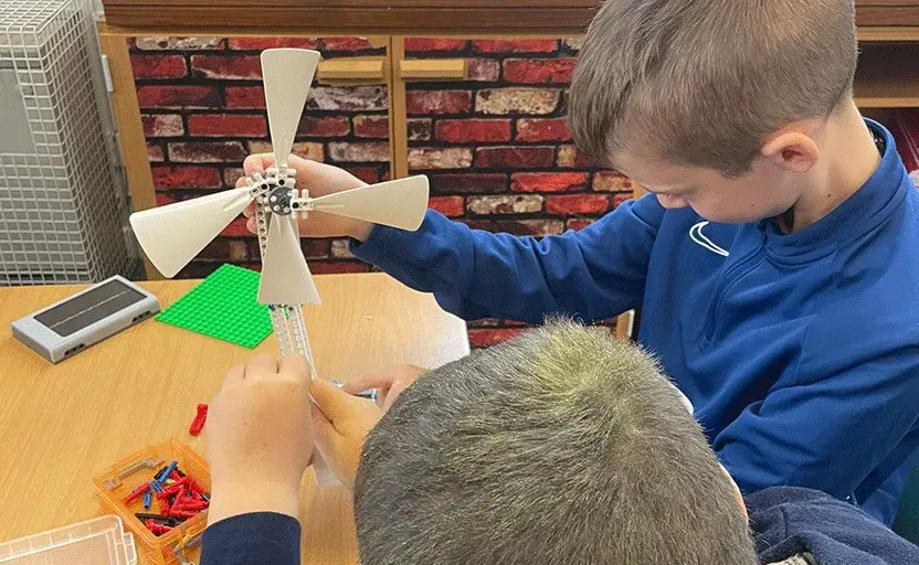 Two male school pupils using LEGO to build a windmill.
