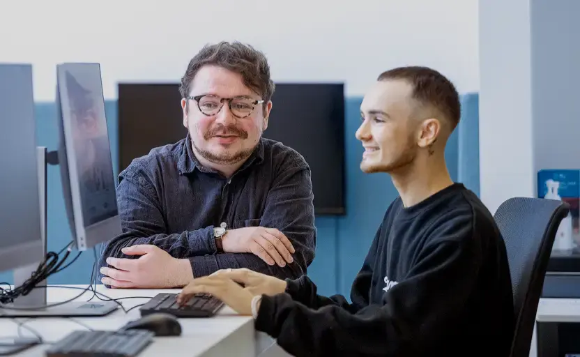 Smiling young man at a computer with a careers adviser