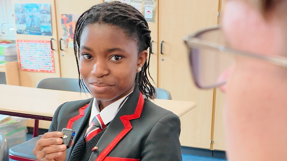Girl in school uniform with microphone smiling at camera