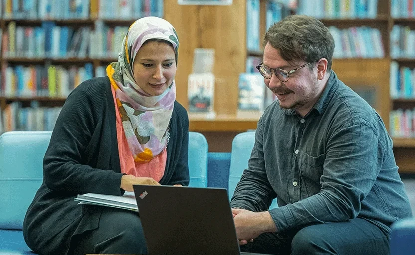 A man and woman looking at a laptop.
