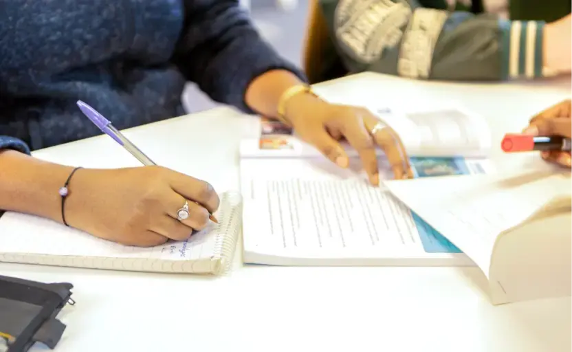 A person is looking at a prospectus and making notes.