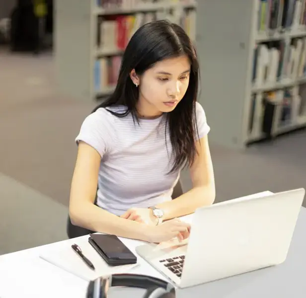 A young woman concentrates while looking at her laptop.