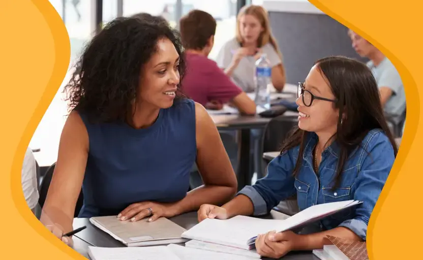 A young student sitting with a textbook open and talking with someone who is giving them advice.