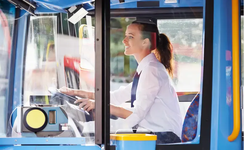 A bus driver sitting behind the steering wheel.