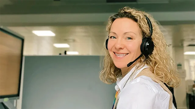 SDS careers adviser smiling while wearing a headset and working at a computer.